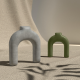 Two modern candle holders against a sand-like background.